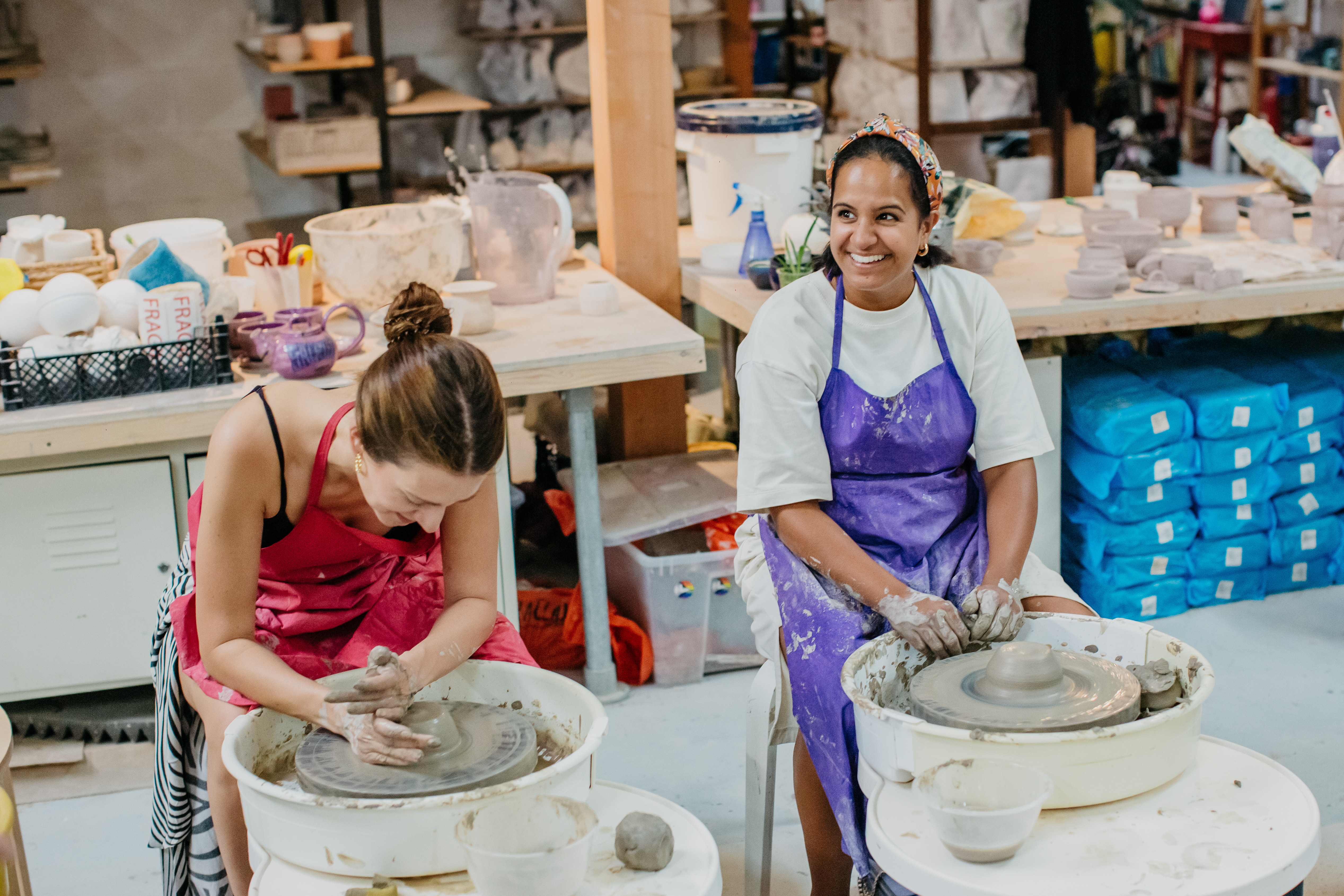 Two friends enjoy a wheel throwing pottery class.
